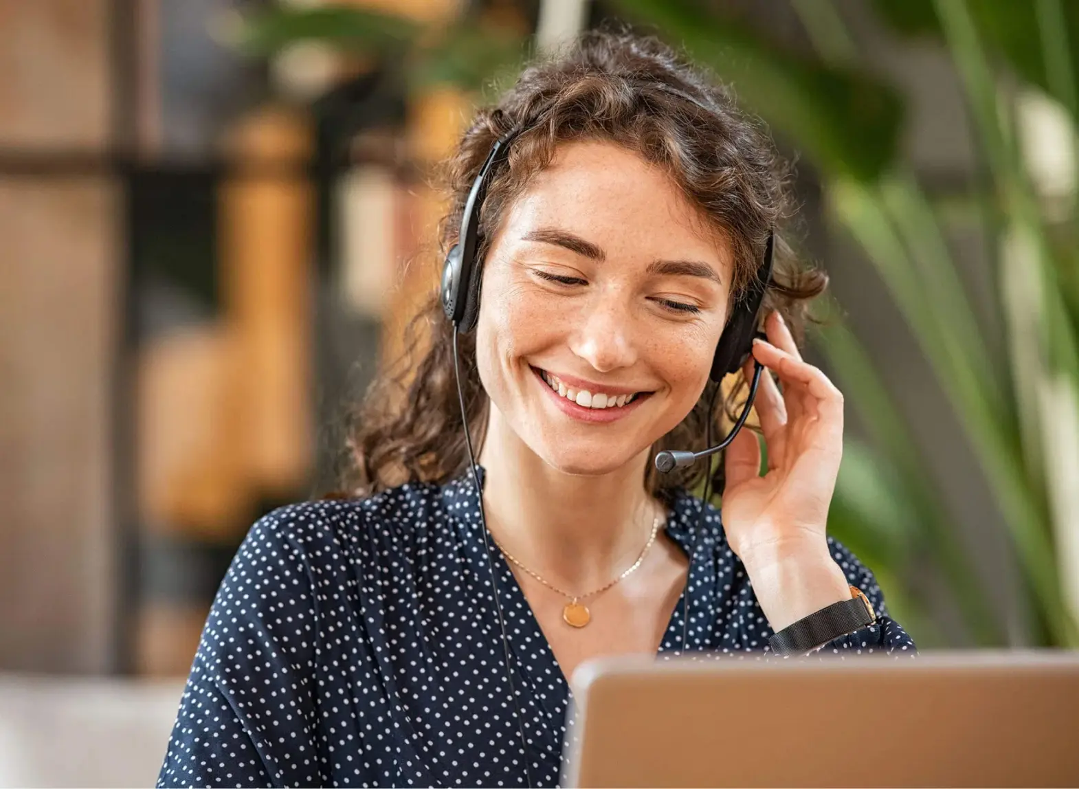 Woman in polka dot shirt smiling with a headset